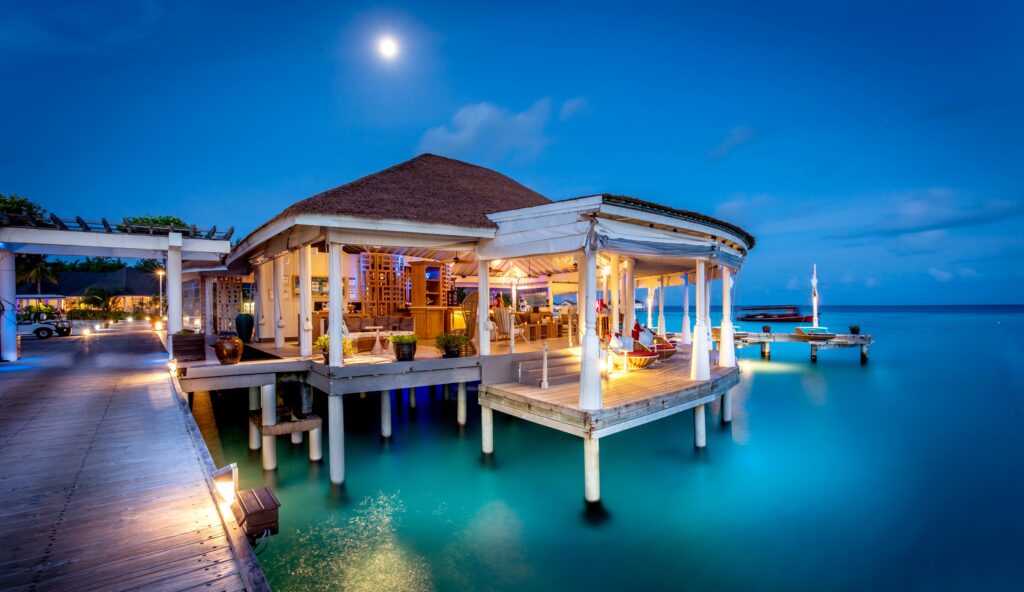 In der Aqua Bar des Centara Grand Island Resort & Spa Malediven relaxen Gäste bei Erfrischungen und Cocktails auf Loungemöbeln oder in Hängematten über dem Meer.