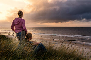 Zwei Menschen, die auf einer Dühne sitzen und auf das Meer der Ostfriesischen Insel Wangerooge gucken