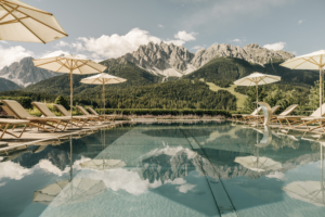Der eindrucksvolle Blick vom Außenpool des Vier-Sterne-Superior-Hotels Leitlhof in Innichen/Südtirol macht Gästen auch beim Schwimmen Lust auf Erkundungstouren in die Dolomiten